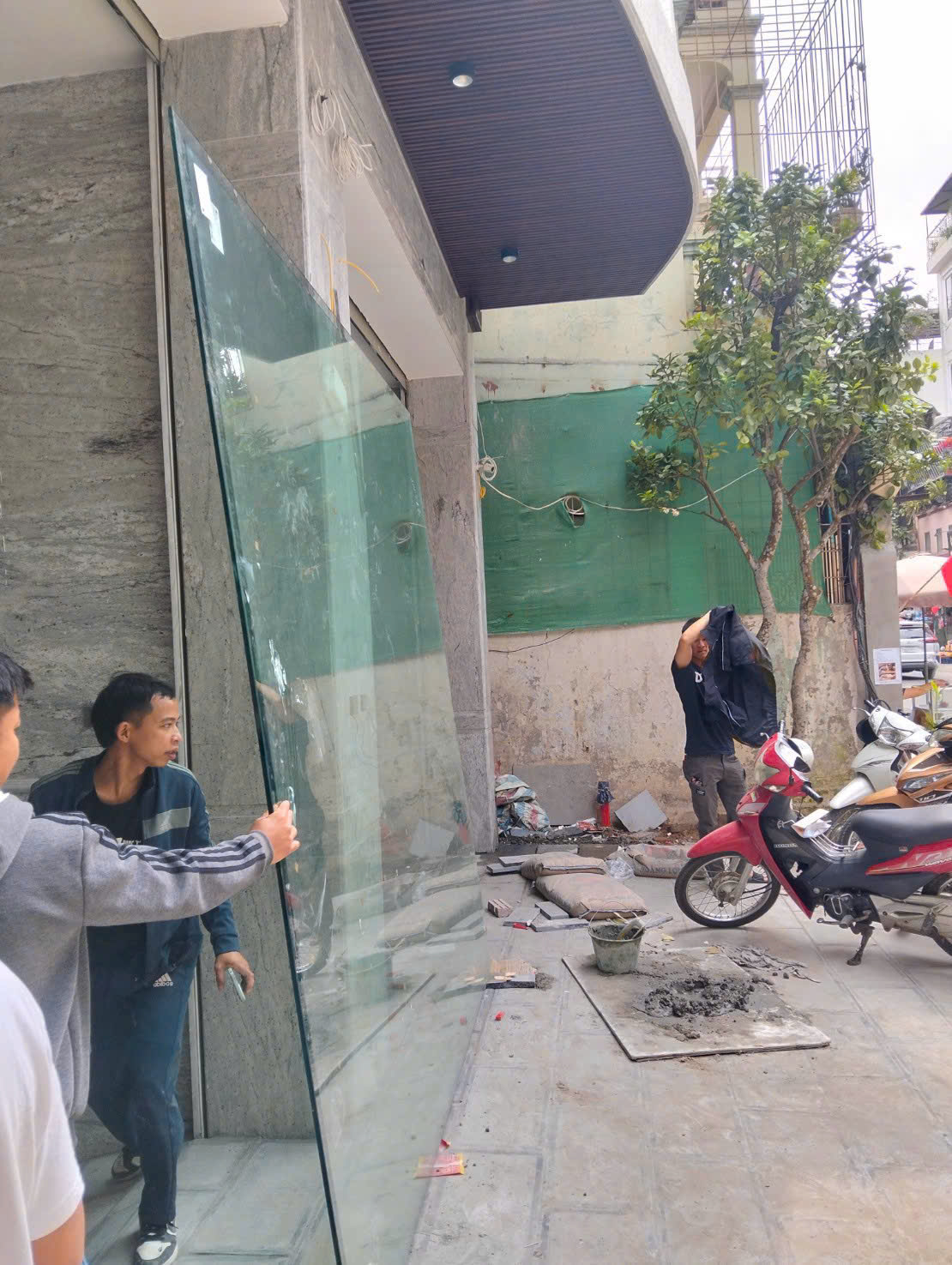 Đưa tấm kính lớn vào vị trí thi công tại mặt tiền công trình